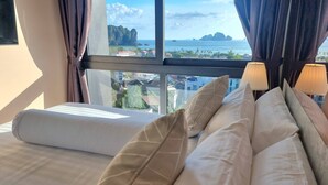 Ett hotellrum med ett stort fönster som erbjuder utsikt över havet och avlägsna öar.