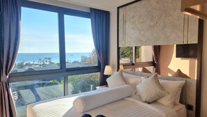 Ett hotellrum med en stor säng, en tv och utsikt över havet.