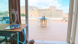 A balcony with a view of a historic fort, a table with chairs, and a decorative mirror. - Casa Sveva – Romantic studio with panoramic terrace in the heart of Otranto (Otranto)