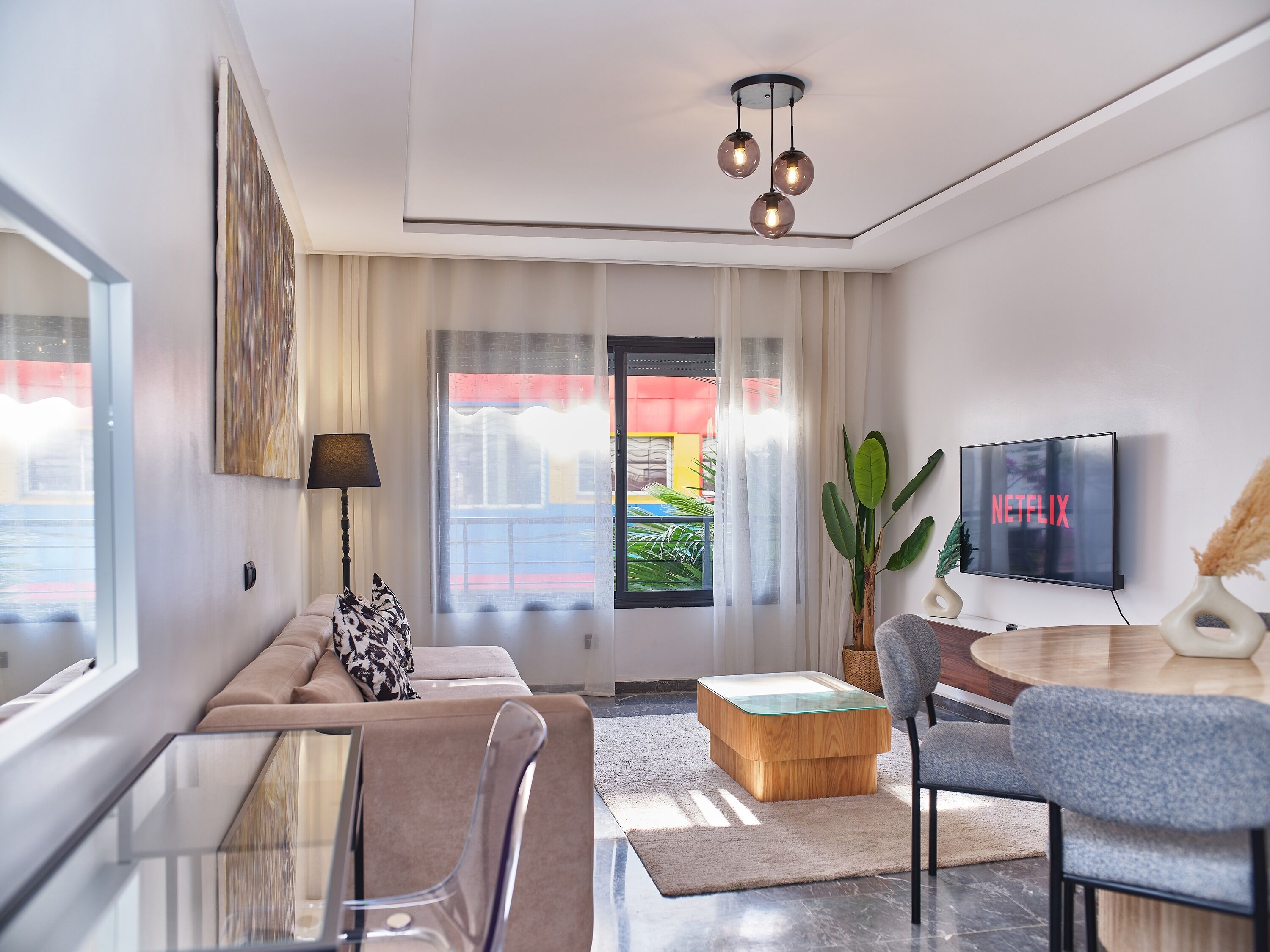Uma sala de estar moderna com um sofá, uma mesa de centro de vidro, uma TV e uma planta.