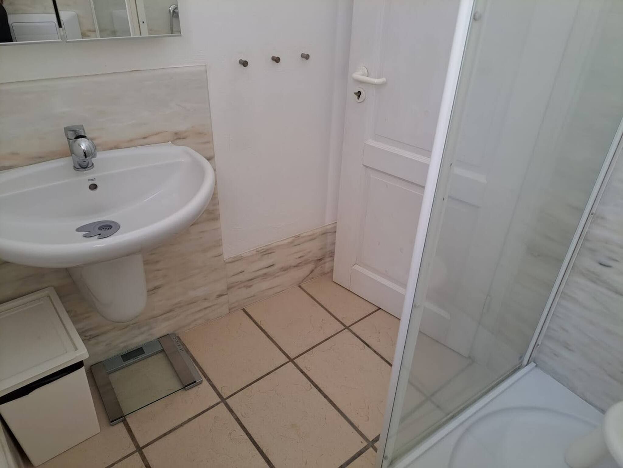 Un bagno con un lavandino bianco, uno specchio, una doccia e un water.