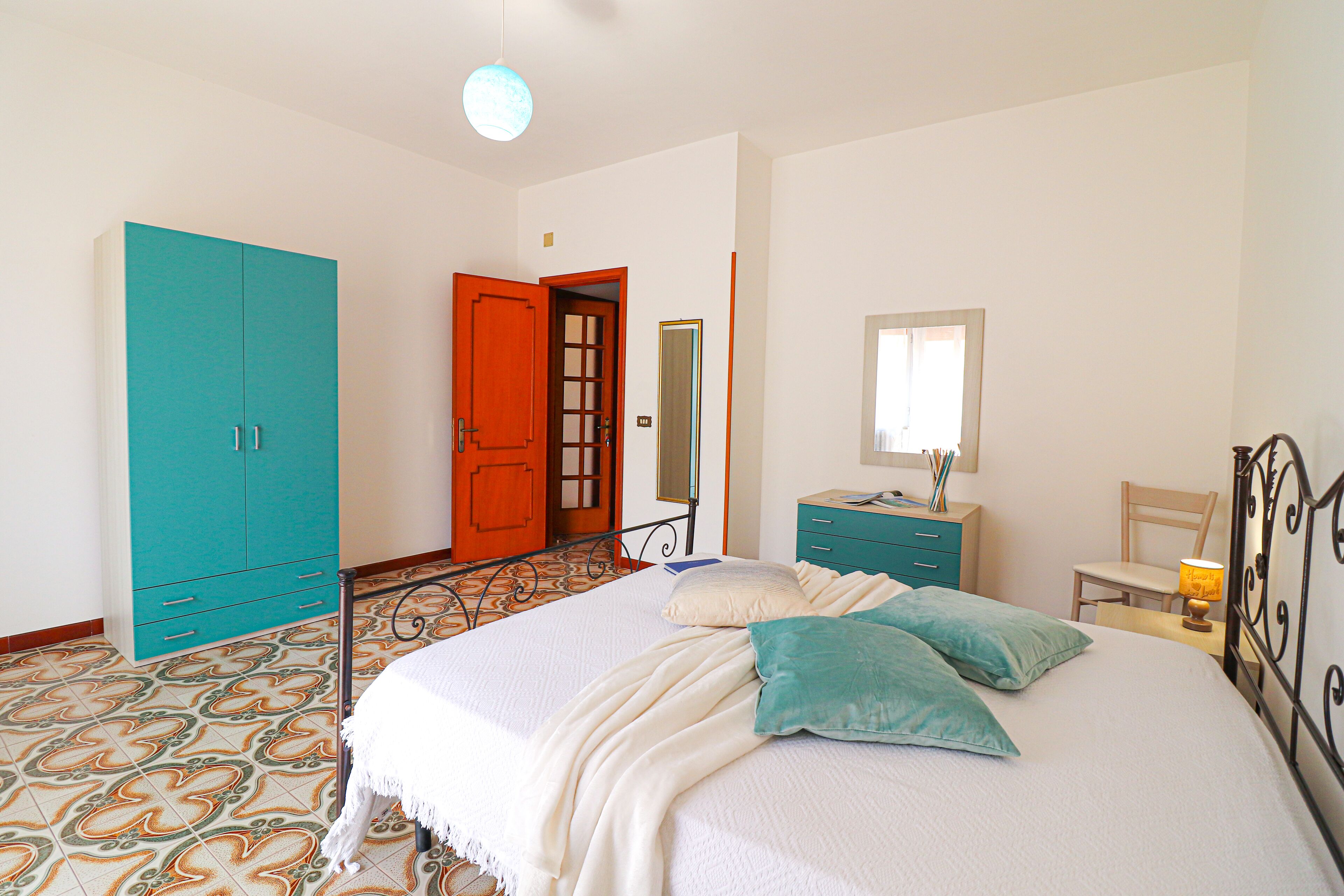 Um quarto com uma cama, um guarda-roupa, uma escrivaninha e uma cadeira.