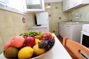 A kitchen with a fruit bowl on the counter, a refrigerator, and a sink.