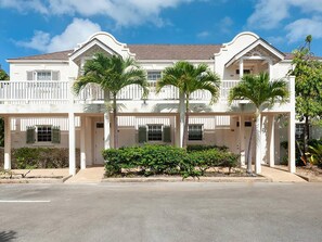 Stunning two-story building with a central entrance and gabled roof, surrounded by lush greenery and palm trees.