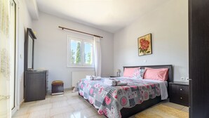 A bedroom with a bed, a nightstand, a dresser, a window, and a painting.