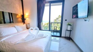 Habitación de hotel con cama, televisión, balcón con vistas y televisor de pared.