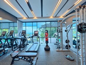 A gym with treadmills, a bench, weightlifting equipment, and large windows offering a view of the outdoors.