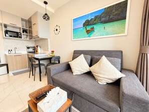 Una sala de estar moderna con un sofá gris, un comedor y una cocina.
