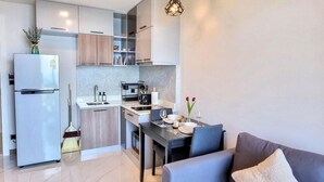 Een moderne keuken met een ingebouwde oven, een eethoek met een tafel en stoelen, en een bank in de woonkamer.