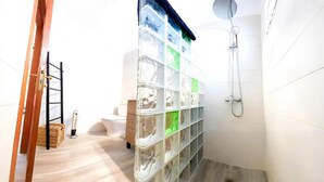 A bathroom with a shower, a toilet, and a storage unit with transparent compartments. - Villa Descansa with private Pool, Air-Conditioning, Sea View, Smart-TV & Wifi (Montaña Roja)