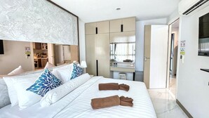 Una habitación de hotel con cama, escritorio, espejo y televisión.