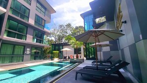 Un hotel moderno con piscina, sillones de descanso y sombrillas.