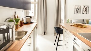 A modern kitchen with a wooden countertop, stainless steel appliances, and a black chair.