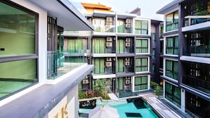 A multi-story hotel with balconies, a swimming pool, and a modern architectural design. - B506 - 1 Bedroom Serviced Apartment Top Floor Pool View at Ao Nang Beach (Tambon Ao Nang)