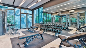 A modern gym with various exercise equipment, large windows, and a view of greenery outside. - B506 - 1 Bedroom Serviced Apartment Top Floor Pool View at Ao Nang Beach (Tambon Ao Nang)