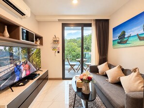 Sala de estar con televisor, sofá, mesa de centro y un cuadro de una playa.