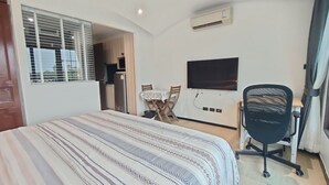 Une chambre à coucher comprenant un lit, un bureau, une chaise, un téléviseur et un appareil de climatisation.