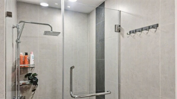 A modern shower area with a glass partition, a handheld showerhead, and a wall-mounted towel rack.