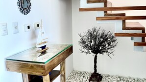 A modern interior with a wooden staircase, a glass-top table with a model ship, decorative wall mirrors, and a bonsai tree. - Spacious apartment w/private rooftop and private cool water jacuzzi  (Punta Cana)