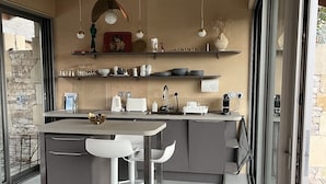 A modern kitchen with a central island, white bar stools, and pendant lighting. - Les Cabanes Insolites del Traouc (Bozouls)