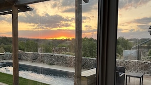 A view from a covered outdoor area with a pool, stone wall, and wooden deck. - Les Cabanes Insolites del Traouc (Bozouls)