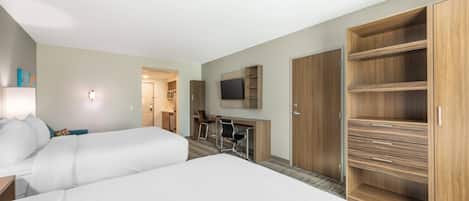 Een hotelkamer met twee bedden, een bureau, een stoel, een televisie en houten kasten.