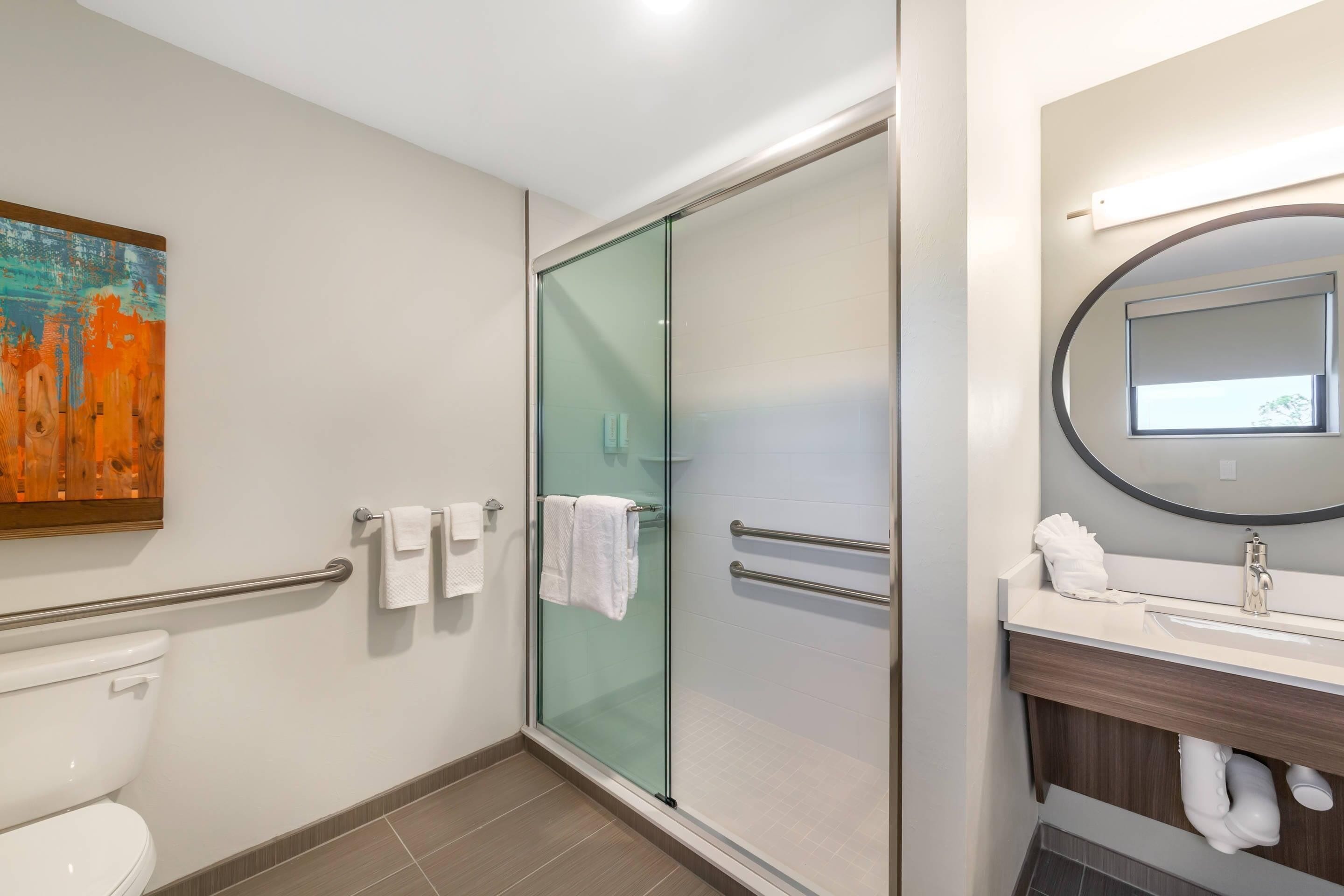 A modern bathroom with a glass shower enclosure, a white toilet, and a vanity with a mirror.