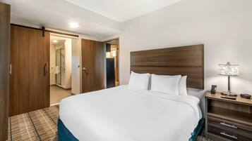 A hotel room with a large bed, wooden wardrobe, and a bedside table with a lamp.