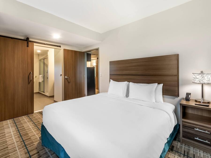 A hotel room with a large bed, wooden wardrobe, and a bedside table with a lamp.