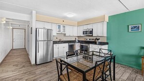 A modern kitchen with white cabinets, stainless steel appliances, and a glass dining table.