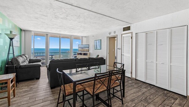 A spacious balcony with a view of the sea, furnished with a sofa, chairs, and a table.