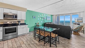 A modern kitchen with white cabinets, a stainless steel oven, and a glass dining table with chairs.
