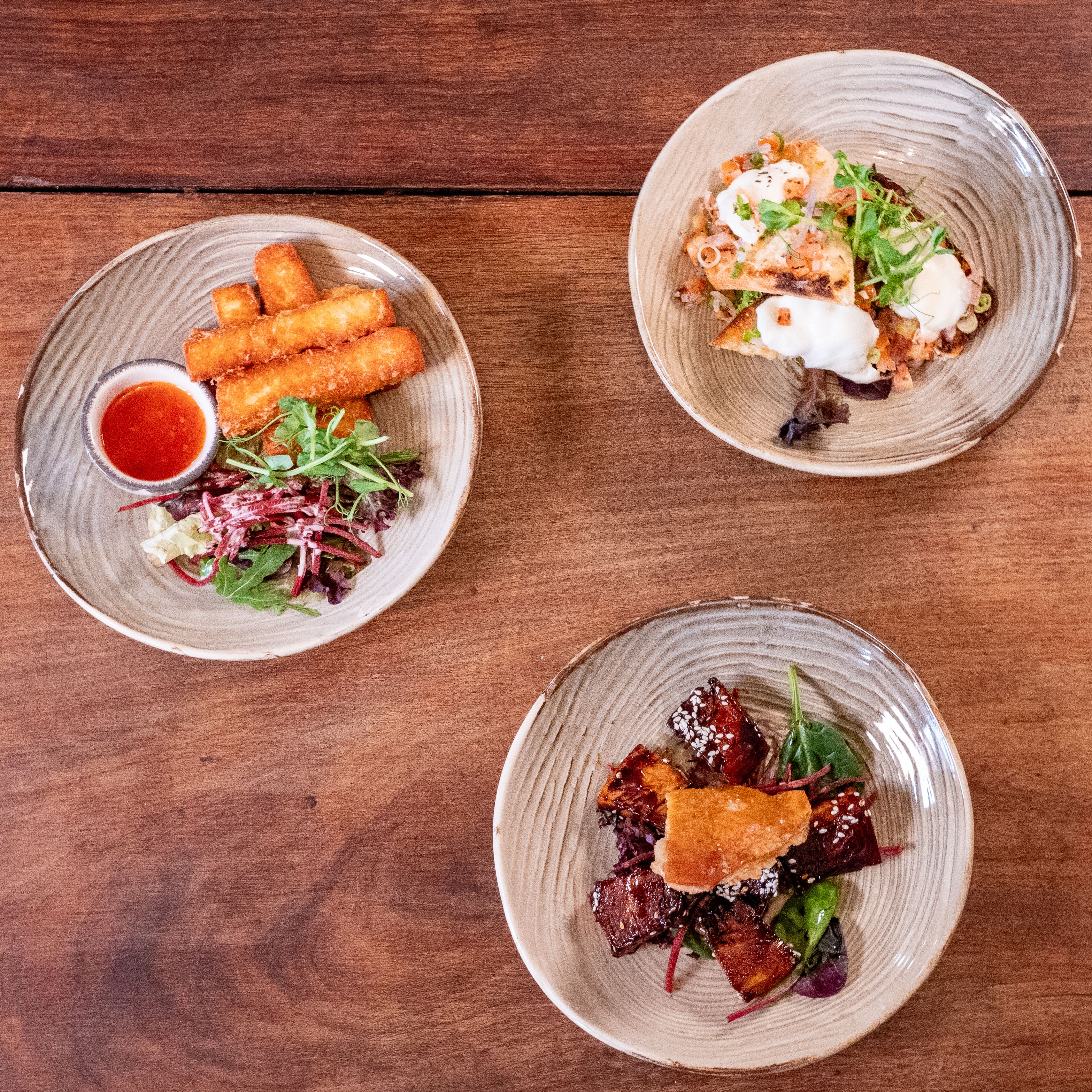 Three plates of food on a wooden table.