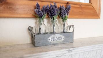 Un cartello di benvenuto con fiori di lavanda in bottiglie di vetro su un ripiano in marmo.