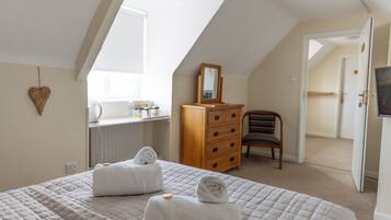 A bedroom with a large bed, a wooden dresser, a chair, and a mirror.