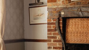 A cozy room with a brick fireplace, a leather couch, and a wooden table. - The Horton Inn (Wimborne)