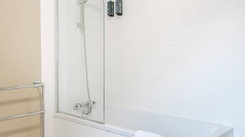 A modern bathroom with a glass-enclosed shower, a white bathtub, and a wooden floor.