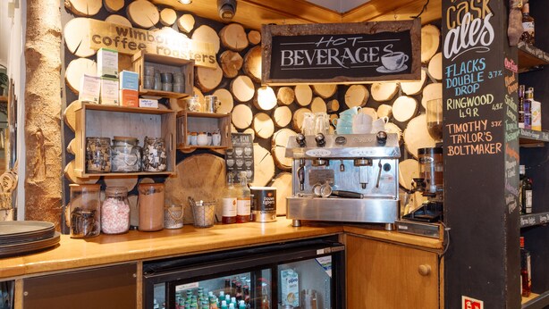 A coffee shop interior with a coffee machine, shelves with jars and mugs, and a sign for 'Hot Beverages'. - The Horton Inn (Wimborne)