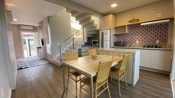 Una cocina moderna con comedor, que incluye una escalera, electrodomésticos integrados y un salpicadero con diseño.