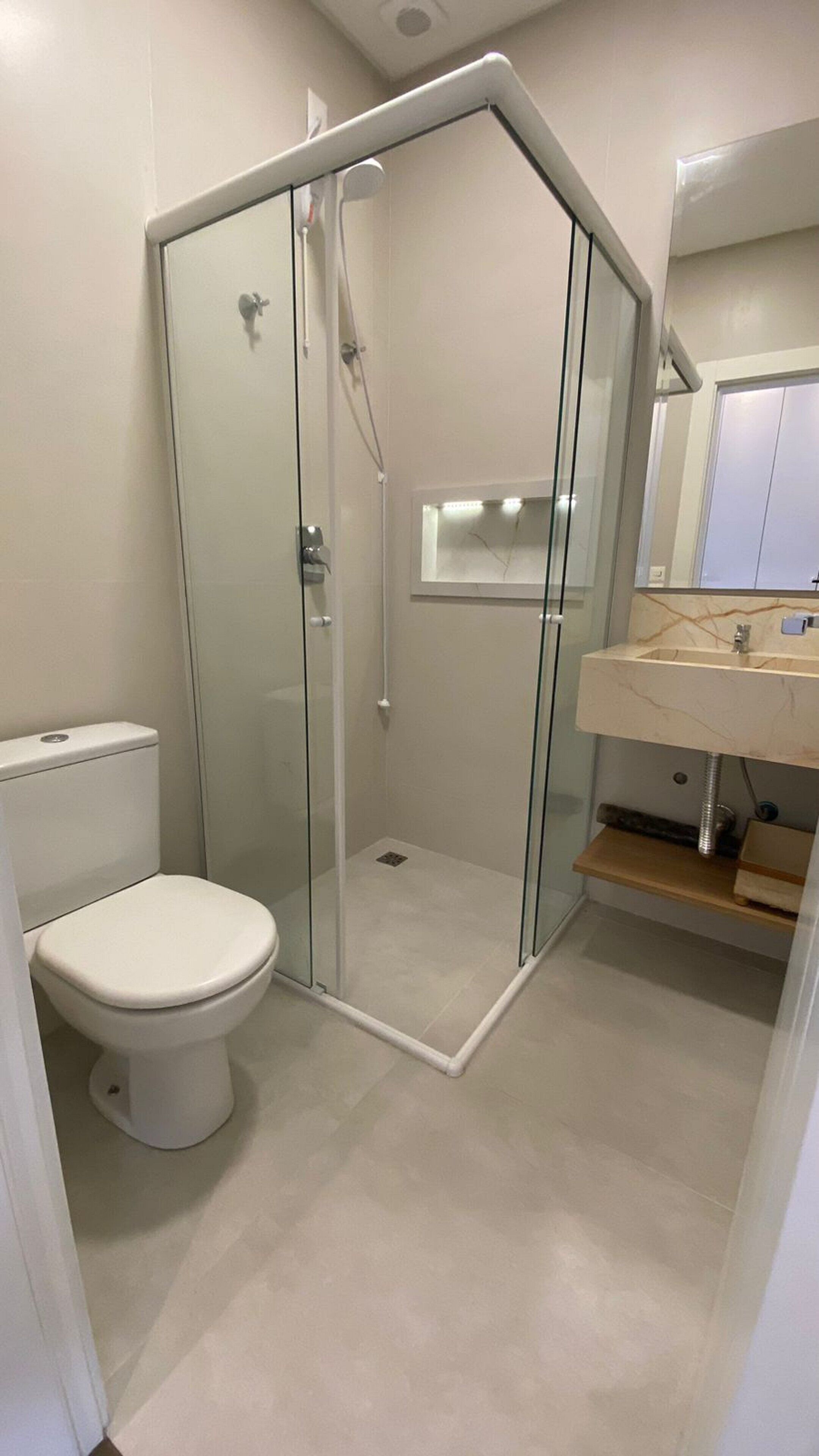 Une salle de bain dotée d’une douche à parois de verre, de toilettes et d’un lavabo avec un plan de travail en marbre.