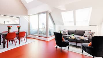 Ein modernes Wohnzimmer mit Essbereich, großen Fenstern und einer geneigten Decke.