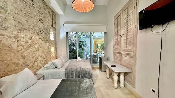 A bedroom with two beds, a dining table, and a TV.