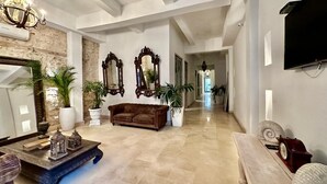 A spacious lobby with a large chandelier, a brown leather sofa, and a coffee table with decorative items.