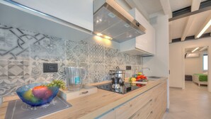 A modern kitchen with a wooden countertop, a built-in stove, and a backsplash with a geometric pattern. - Ulivo Apt - Palazzo Palermo 1817 A/c, 2BR Sleeps 5 (Valeggio sul Mincio)