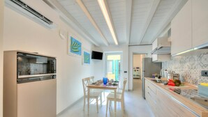 A modern kitchen with a built-in oven, a dining table with chairs, and a TV mounted on the wall. - Ulivo Apt - Palazzo Palermo 1817 A/c, 2BR Sleeps 5 (Valeggio sul Mincio)