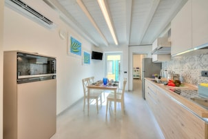 Una cocina moderna con horno empotrado, una mesa de comedor con sillas y un televisor montado en la pared.