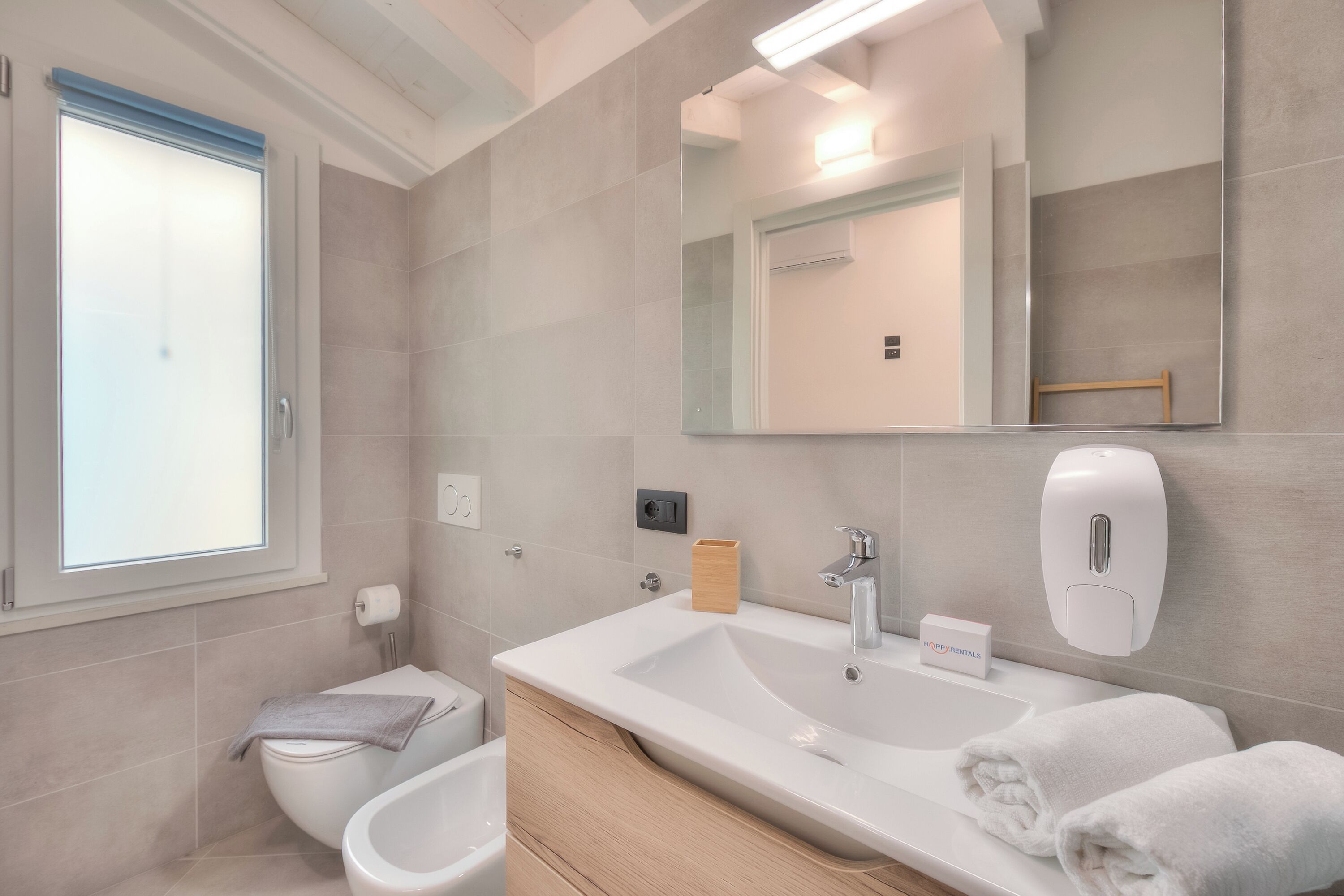 Une salle de bain moderne avec un grand lavabo, un miroir et des toilettes.