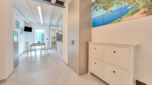 A modern interior with a dining area, a white cabinet, and a painting of a landscape. - Ulivo Apt - Palazzo Palermo 1817 A/c, 2BR Sleeps 5 (Valeggio sul Mincio)