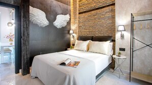 A modern bedroom with a large bed, a brick wall, and decorative wall art.