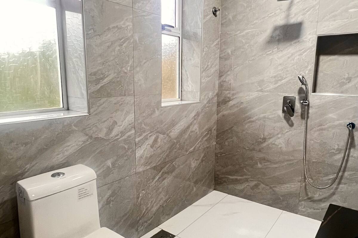 A modern bathroom with a toilet, a shower, and a sink.